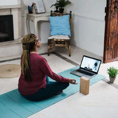 African senior woman doing online yoga lesson at home during coronavirus outbreak - Old female person meditating using computer laptop - Technology and zen concept - Focus on hand