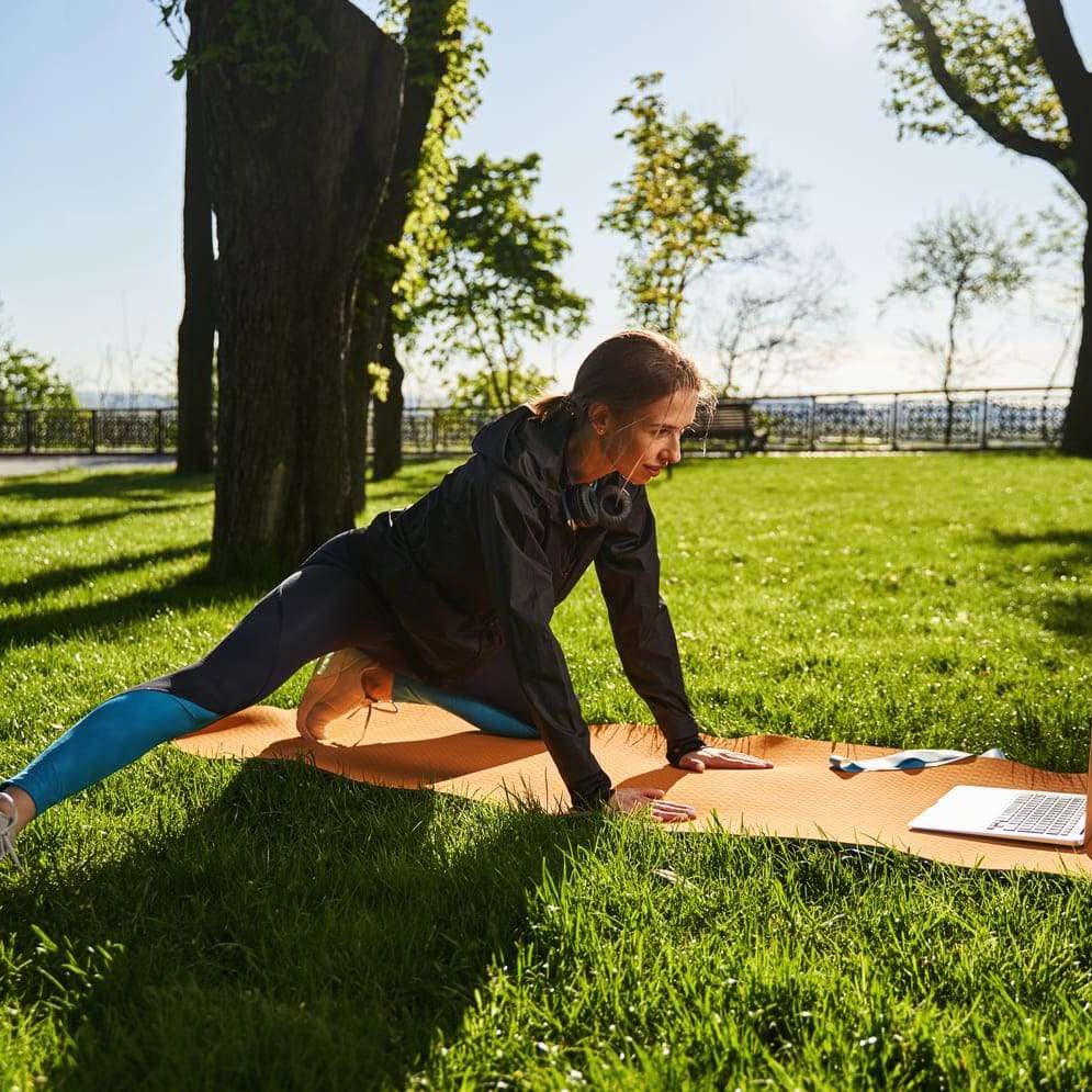 joyful-woman-exercising-in-park-with-laptop-2024-10-18-17-49-18-utc